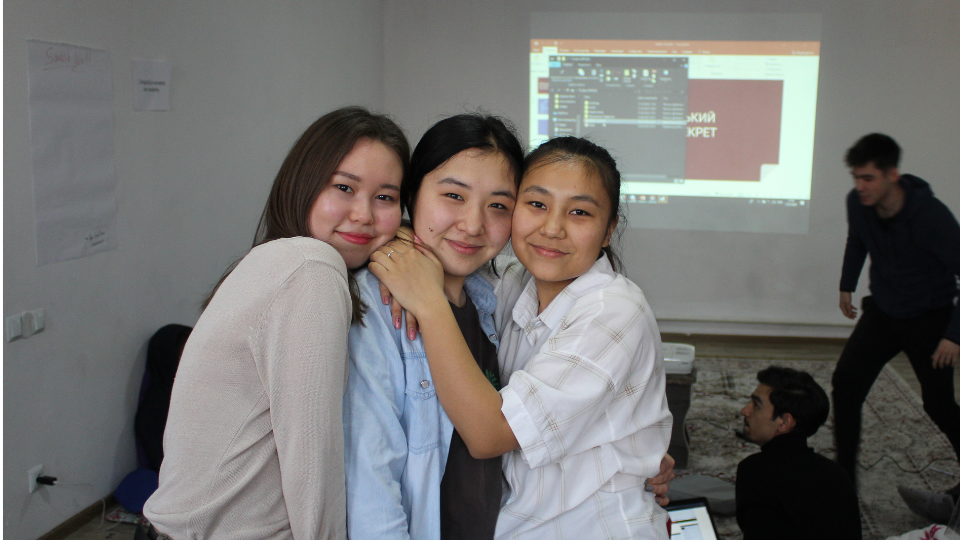 3 girls taking a photo together infront of a projector